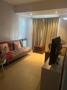 a living room with a couch and a tv at Departamento céntrico en Lobos in Lobos