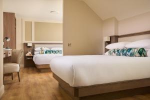 una habitación de hotel con 2 camas y una silla en The James Hotel en Tralee