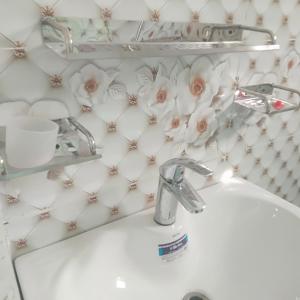 a bathroom sink with pink roses on the wall at Patriata Luxury Suits in Murree