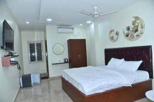a bedroom with a white bed and a television at The Paradise Guest Inn in Nellore
