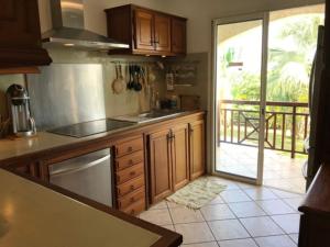 Saint-PaulにあるVilla Les Talipots avec piscine et vue mer classée 5 étoilesのキッチン(木製キャビネット付)が備わり、パティオの景色を望めます。