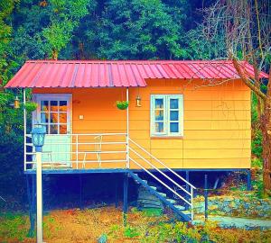 a small yellow and orange house with a red roof at Aaroham Resort Shimla ! Luxury Cottage by Aamod Group in Shimla