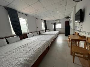 szereg łóżek w pokoju ze stołem w obiekcie Hoài Thu Hotel Vũng Tàu w mieście Vung Tau