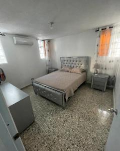 a bedroom with a bed and two tables and two windows at Casa Blanca in Santo Domingo