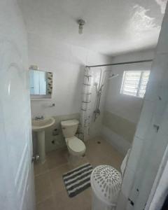 a white bathroom with a toilet and a sink at Casa Blanca in Santo Domingo