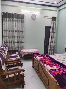 a bedroom with two beds and a clock on the wall at Guru Kripa Guest House ( Home Stay ) in Ayodhya