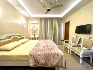1 dormitorio con 1 cama, 2 sillas y TV en National Luxury Apartments - 2 Bed Room, en Lahore
