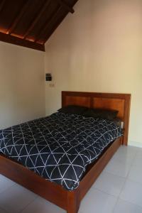 a bedroom with a bed with a black comforter at Avocado homestay in Tetebatu