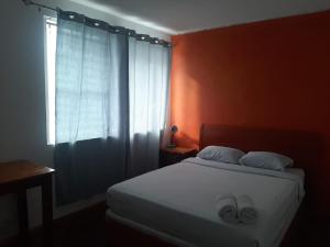 una camera con un letto e una finestra con due pantofole di Lost in San Jose Hotel & Hostel a San José