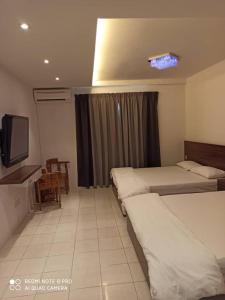 Cette chambre comprend deux lits et une télévision. dans l'établissement Sunshine Lot 10 Pangkor, à Kampong Sungai Udang