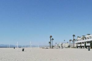 a sandy beach with palm trees and buildings at STAY AT THE HERMOSA PIER LUXE Studio in Hermosa Beach