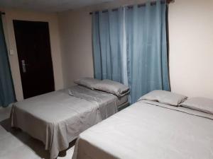 two beds in a room with blue curtains at The best place to rest near Tocumen Airport in Panama City