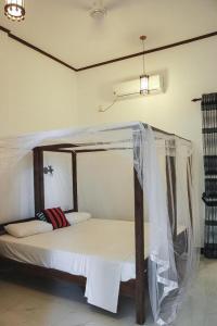 1 cama con dosel en una habitación en Sunset View Beach Hotel, en Arugam Bay