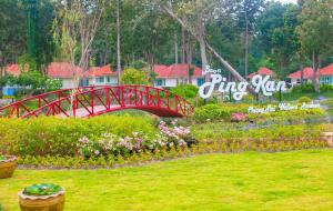 un puente rojo sobre un jardín con flores en un parque en Baan Pingkan Wellness Resort en San Kamphaeng