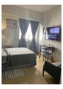 een slaapkamer met een bed, een tafel en een televisie bij Boheme Condotel at Trees Residences Studio2 in Manilla