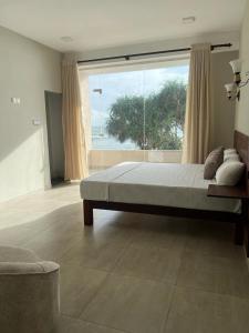 ein Schlafzimmer mit einem großen Bett und einem großen Fenster in der Unterkunft Sevenra Grand Beach Hotel in Ambalangoda