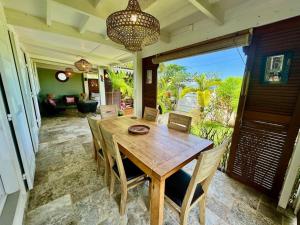 a dining room with a wooden table and chairs at Villa Pinky Créole vue mer proche plage in Trois Bassins