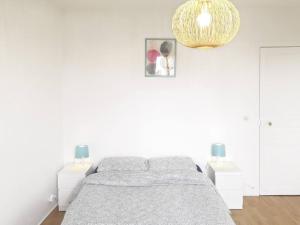 a white bedroom with a bed and two night stands at Lovely three-room apartment near metro station in Saint-Denis