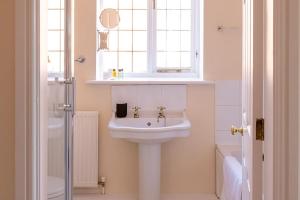 a white bathroom with a sink and a window at Chaveney Cottage in Quorndon