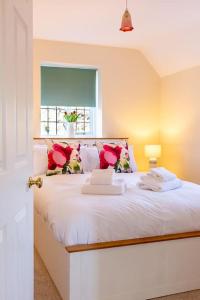 a bedroom with a white bed with a window at Chaveney Cottage in Quorndon