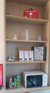 un four micro-ondes assis sur une étagère avec des livres dans l'établissement SERENA SWEET HOUSE, à SantʼAndrea Apostolo dello Ionio