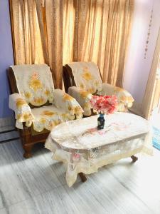 two chairs and a table with a vase of flowers at Bikaner bliss - guest suite in Bikaner