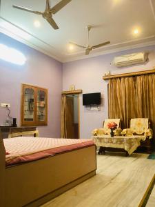 a bedroom with a bed and a chair and a tv at Bikaner bliss - guest suite in Bikaner