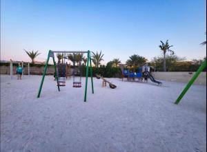 une aire de jeux avec balançoires et matériel de jeu dans le sable dans l'établissement Luxury, One bedroom apartment Ocean view, à Ras al Khaimah