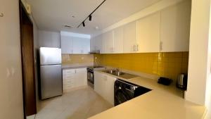 La cuisine est équipée de placards blancs et d'un réfrigérateur en acier inoxydable. dans l'établissement Luxury, One bedroom apartment Ocean view, à Ras al Khaimah