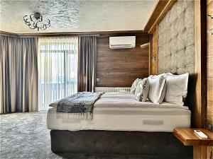 a bedroom with a large bed and a large window at V Chalet Residence in Velingrad