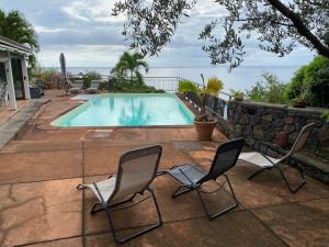 a pair of chairs sitting next to a swimming pool at Villa Rocher sur mer avec piscine vue mer in Saint-Leu