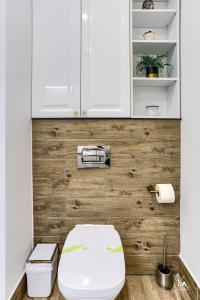 a bathroom with a white toilet and a wooden wall at Sika Garden Apartment- garaj privat cu intrare direct in apartament și grădină in Arad