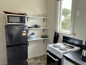 a kitchen with a refrigerator and a microwave and a stove at Oamaru Villa in Oamaru
