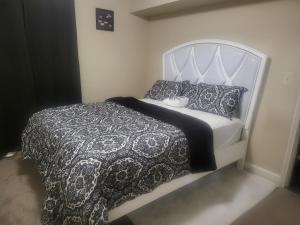 a bed with a black and white blanket and pillows at kaysgroove in Alexandria