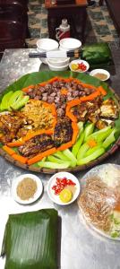 a table with a large plate of food on it at Homstay Hưng Yên - Long Cốc 