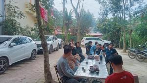 eine Gruppe von Menschen, die an einem Tisch sitzen und Autos parken in der Unterkunft Homstay Hưng Yên - Long Cốc 