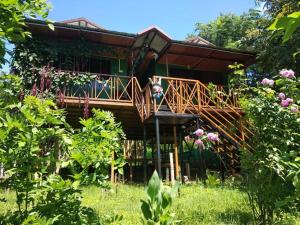 a wooden house with a deck in a garden at Mist Valley in Masinagudi