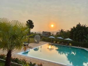 una piscina con puesta de sol en el fondo en Ganesha Kampot Resort, en Kampot