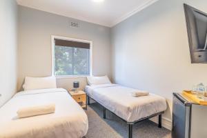 two beds in a small room with a window at K2 Brisbane in Brisbane