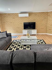 ein Wohnzimmer mit einem Sofa und einem TV in der Unterkunft Sandstone Family Apartment in Grindelwald