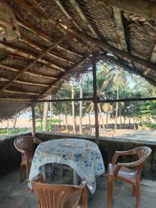 einen Tisch und Stühle unter einem Dach in der Unterkunft Raaga on the Beach in Kannur