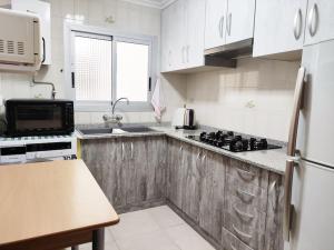 uma cozinha com armários brancos, um lavatório e um frigorífico em Acogedor y competo apartamento. em Villajoyosa