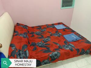 a bed in a room with a red blanket at Sinar Maju Homestay in Tanah Rata