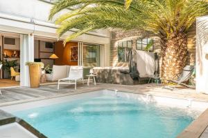 una piscina en un patio trasero con una palmera en Superbe maison d'architecte entièrement climatisée avec piscine et spa professionnel, en Talence