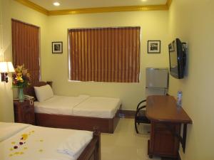 a room with two beds and a desk and a television at Golden House International Hotel in Phnom Penh