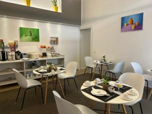 a dining room with tables and white chairs at Zeta Rooms in Caserta