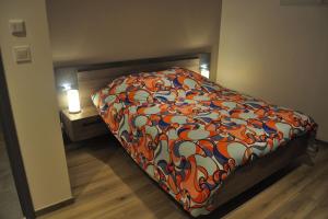 um quarto com uma cama com um cobertor colorido em Gîte la p'tite rivière em Saint-Nabord