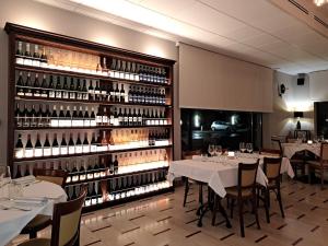 a restaurant with tables and a large wall of wine bottles at Hotel Brixellum in Brescello +21 photos