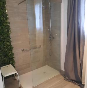 ducha con puerta de cristal y taburete en Bonito Alojamiento F en Valencia