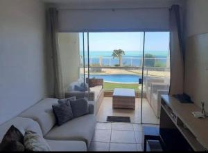 uma sala de estar com um sofá e vista para uma piscina em Apart Canoa Quebrada vista mar- condominio fechado em Aracati